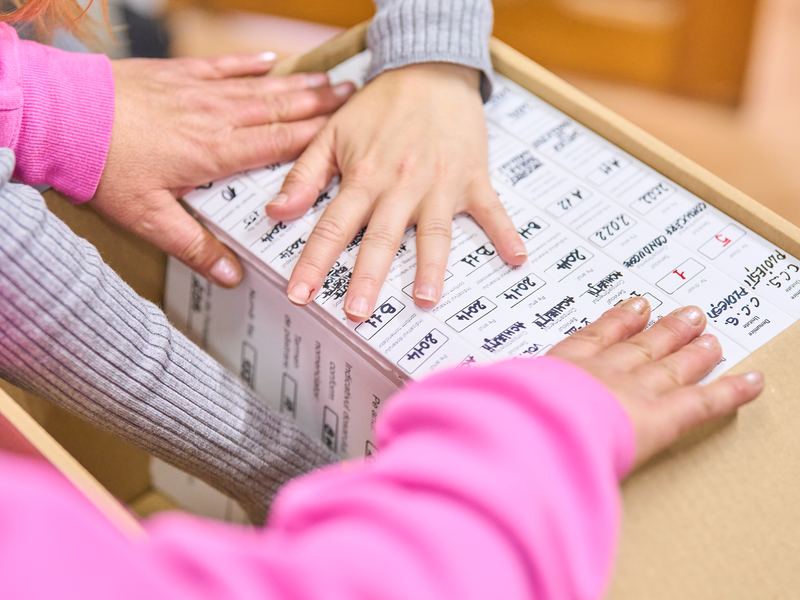 Arhiviste care așază dosarele inventariate într-o cutie de arhivă