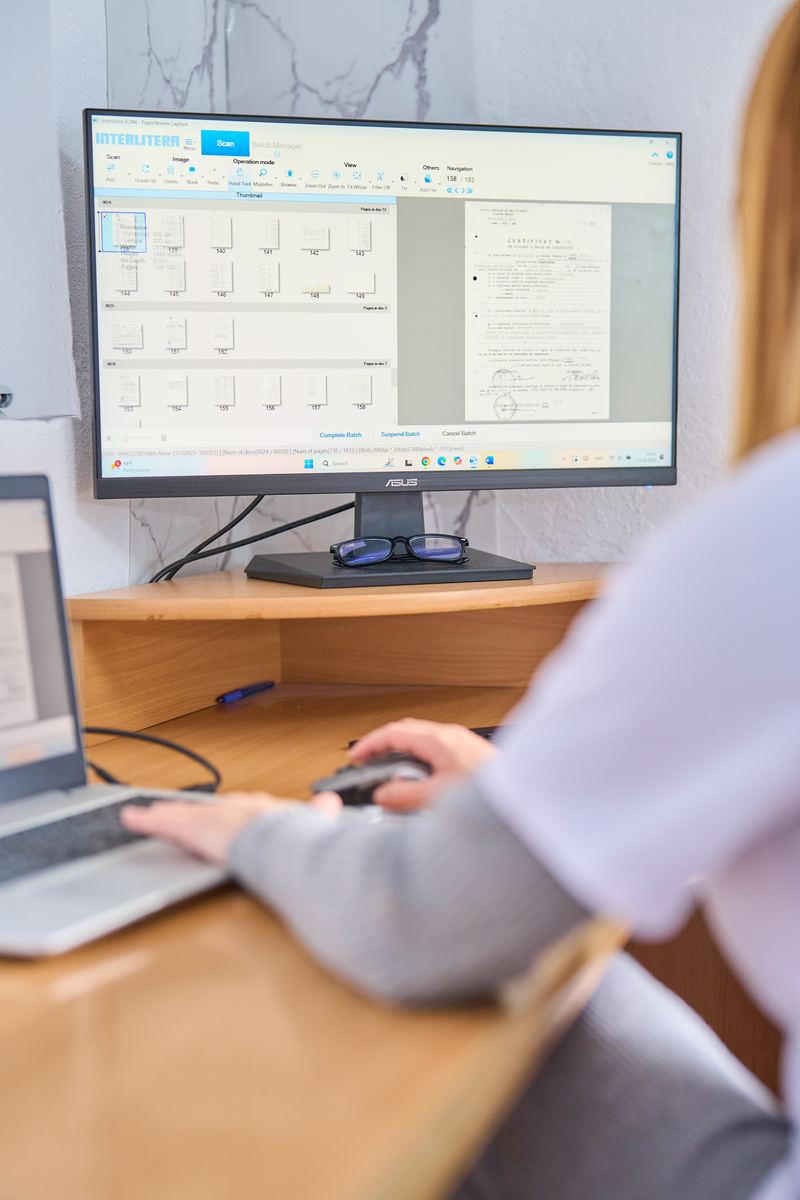 Arhivistă care lucrează la calculator cu documente scanate