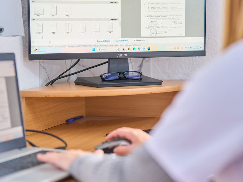 Arhivistă care lucrează la calculator cu documente scanate